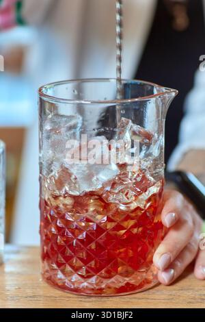 Il barman spreme a mano il succo fresco di lime nel bicchiere per preparare il cocktail Caipirinha al bancone del bar. Foto Stock
