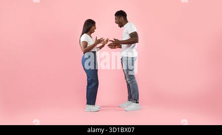 La coppia si confronta durante una discussione in mezzo a uno sfondo rosa Foto Stock