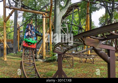 Una vivace carrozza a tema rana verde a Duinrell attraversa un'area boscosa con ciclisti entusiasti che si divertono per tutta la famiglia. Wassena Foto Stock