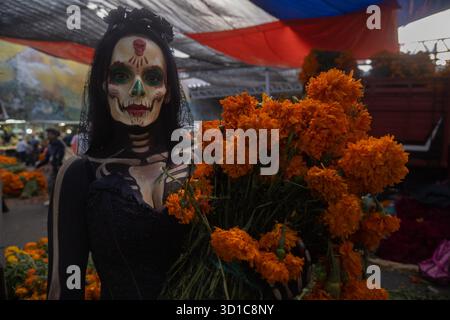 Città del Messico, Messico. 26 ottobre 2025. Una donna con il viso dipinto come un teschio tiene fiori cempasuchil al mercato giamaicano per le celebrazioni del giorno dei morti. Il 26 ottobre 2025 a città del Messico, Messico. (Foto di Marco Gonzalez/ Eyepix Group/Sipa USA) credito: SIPA USA/Alamy Live News Foto Stock