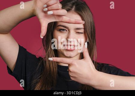 cornice per ritratti giocosa, ritratto che enfatizza l'energia giovanile mentre la donna crea una cornice giocosa intorno a lei Foto Stock