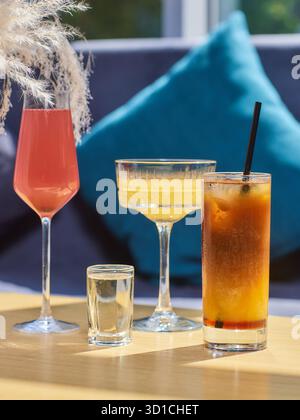 Cocktail sul tavolo. Bevande di colori diversi in bicchieri diversi su un tavolo di legno scuro su sfondo sfocato del ristorante. Concetto bar, alcol Foto Stock