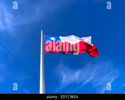 Una grande bandiera cilena che sventola orgogliosamente in alto contro un cielo azzurro. I colori rosso, bianco e blu della bandiera nazionale del Cile Foto Stock