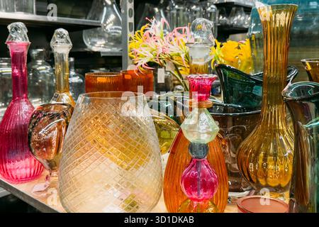 Vetreria colorata soffiata a mano esposta sugli scaffali di un negozio vintage. I temi includono la sostenibilità nell'artigianato, le tendenze dell'arredamento degli interni e il design artigianale Foto Stock