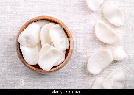 Cracker di gamberi, patatine di gamberi in una ciotola di legno, su lino. Mazzo di cracker fritti in profondità, realizzati con un impasto di tapioka, gamberi macinati e condimenti. Foto Stock
