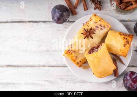 Vertuta, torte fatte in casa con marmellata di prugne dolci e ripieno piccante, con cannella, su uno sfondo di cucina in legno con succose prugne scure e spi Foto Stock
