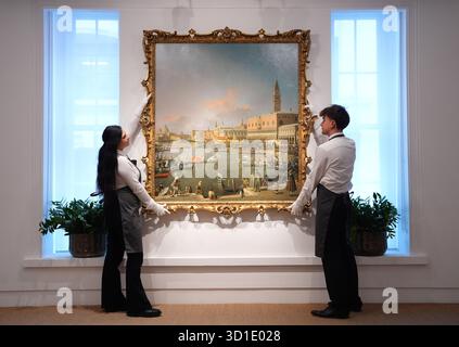 I tecnici d'arte CHE RIMUOVONO L'EMBARGO gestiscono il capolavoro di Canaletto "Venice, the Bucintoro at the Molo on Ascension Day", esposto presso la casa d'aste Christie's nel centro di Londra. Il Vecchio Maestro raffigurante una vista di Venezia fu dipinto da Canaletto in Inghilterra su commissione della famiglia reale, che la tenne per 200 anni. Il pezzo sarà in mostra a Londra a Christie's King Street dal 27 novembre al 2 dicembre, prima di essere messo in vendita con una stima di 30 milioni di dollari americani alla New York Old Masters sale nel febbraio 2026. Il dipinto e' apparso all'asta per l'ultima volta 20 anni fa, dove e' fratello Foto Stock