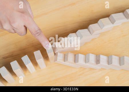 Piano di rischio aziendale protezione immobiliare. Man Hand blocca blocchi di legno da molte file che cadono blocchi di legno come il domino. Idee assicurative per evitare perdite Foto Stock