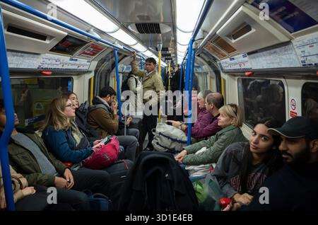 I passeggeri della metropolitana di Londra viaggiano con le loro valigie e i loro bagagli verso Heathrow con una carrozza Piccadilly Line, nel centro di Londra, Inghilterra, Regno Unito Foto Stock