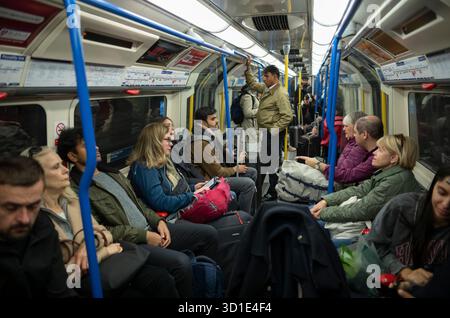 I passeggeri della metropolitana di Londra viaggiano con le loro valigie e i loro bagagli verso Heathrow con una carrozza Piccadilly Line, nel centro di Londra, Inghilterra, Regno Unito Foto Stock