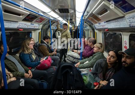 I passeggeri della metropolitana di Londra viaggiano con le loro valigie e i loro bagagli verso Heathrow con una carrozza Piccadilly Line, nel centro di Londra, Inghilterra, Regno Unito Foto Stock