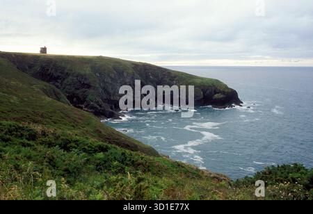 Scogliere lungo la costa meridionale dell'Irlanda. Ardmore Watch Tower in cima alla scogliera. Foto Stock