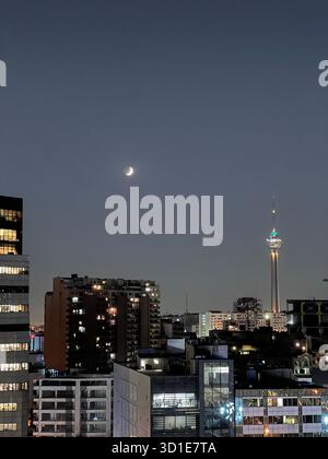 Vista notturna di Teheran, Iran, la Torre Milad che splende sotto una luna crescente sopra il luccicante skyline della città. Foto Stock