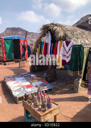 Una donna locale che vende artigianato e vestiti colorati in un mercato tradizionale sull'isola di Hormuz, Iran. Foto Stock