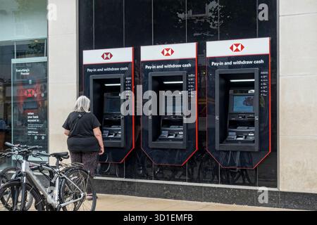 Persona che utilizza un bancomat all'esterno della filiale della banca HSBC nel centro città di York North Yorkshire Inghilterra Regno Unito Gran Bretagna Foto Stock