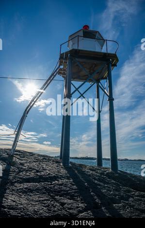 Kvalen fyr, il faro si erge su una costa rocciosa sotto un cielo azzurro, con il sole che splende brillantemente, colpo verticale, Haugesund, Norvegia Foto Stock