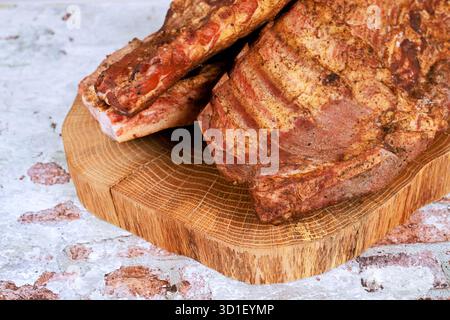 Le costolette di maiale affumicate ricoperte di spezie si trovano su una tavola di legno che evoca il senso della preparazione culinaria. Foto Stock
