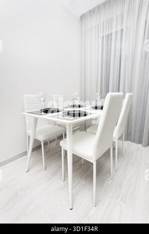 Tavolo bianco minimalista servito con piatti neri in un ristorante o in soggiorno Foto Stock