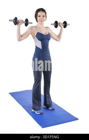 Una giovane istruttrice di fitness mostra la posizione iniziale di una spalla in piedi, isolata sul bianco Foto Stock