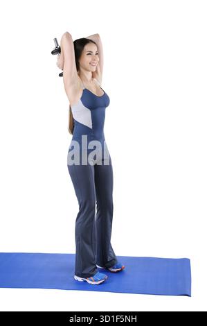 Young Woman mostra la posizione iniziale di Standing Triceps Extension Dumbbell Behind Head Workout, isolato su bianco Foto Stock