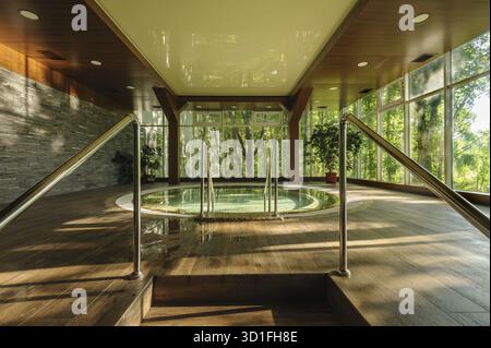 Grande e lussuosa vasca jacuzzi rotonda nel verde centro spa, la mattina presto Foto Stock