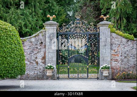 Cancello in ferro battuto dal design classico in uno splendido giardino verde. Foto Stock