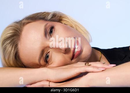 Una donna bionda con capelli corti gode un momento di relax, vestita con un elegante abito nero. Foto Stock