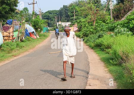 Bheemili, Visakhapatnam, Andhrapradesh - 10 settembre 2025: Un vecchio che cammina su una strada del villaggio tenendo in mano un bastone. Vecchio indiano. Foto Stock