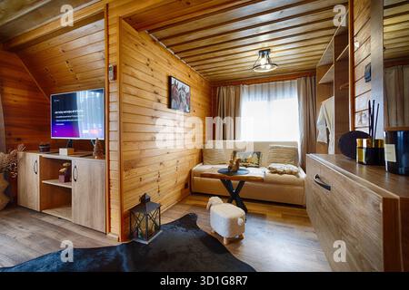 Soggiorno in cabina in legno caldo e invitante con arredamento rustico, illuminazione soffusa e dettagli accoglienti. Uno spazio perfetto per il relax e il comfort nella natura. Foto Stock