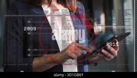 Un tablet, una donna d'affari in un blazer della marina che analizza i server nel data center, con sovrapposizione rossa HUD Foto Stock