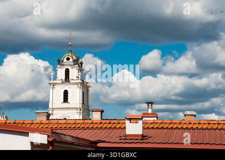 Vilnius, Lituania - 1 luglio 2015 - storica torre della chiesa con croce sotto il cielo nuvoloso in un ambiente urbano. Foto Stock