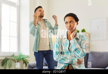Giovane in piedi a casa e gridare contro la moglie afroamericana in lite. Foto Stock