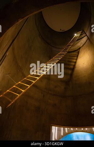 Cattedrale dell'aurora boreale, alta, Norvegia, la scala sale su una struttura circolare in calcestruzzo poco illuminata, illuminata da un faretto Foto Stock