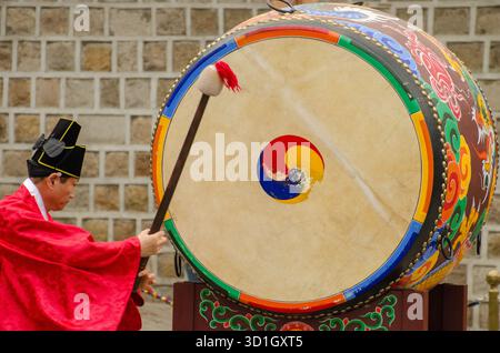 Seoul, Gyeonggi, Corea del Sud. 31 marzo 2015: Un uomo in tradizionale abbigliamento coreano suona un grande tamburo colorato all'aperto. Foto Stock