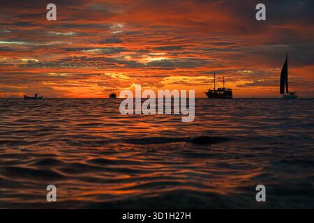 tramonto croato sul mare con quattro barche all'orizzonte Foto Stock