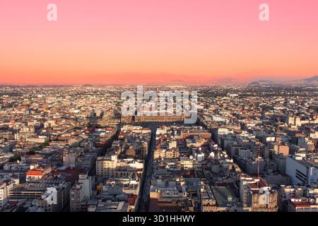 Vista aerea di città del Messico al tramonto con cielo rosa e luce dorata che illuminano lo skyline del centro, mostrando il vasto paesaggio urbano dell'architettura cittadina Foto Stock