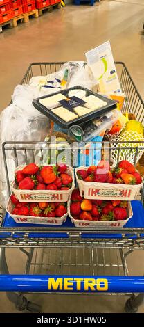 Belin, Germania - 30 maggio 2025: Il carrello della spesa è pieno di fragole fresche, formaggio e vari articoli in negozio. Ospedale Foto Stock