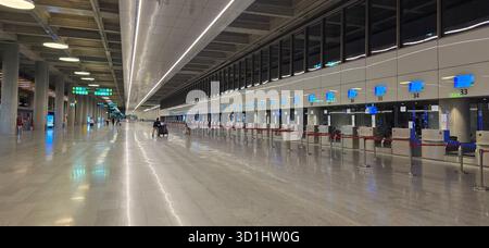 Doloman, Turchia - 25 aprile 2025: Moderno terminal aeroportuale dotato di banchi check-in vuoti e illuminazione luminosa. Foto Stock