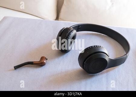 Cuffie wireless e un tubo per fumatori di menta su carta bianca, che suggerisce tabacco non fumatori Foto Stock