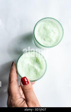 Vista dall'alto di una donna che cerca due lattine di matcha Iced su sfondo bianco Foto Stock