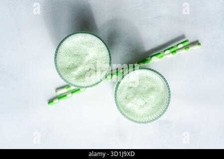 Vista dall'alto di due lattine di matcha Iced e cannucce da bere su sfondo bianco Foto Stock