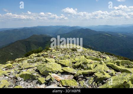Paesaggio estivo dei Carpazi. prato con enormi pietre tra l'erba in cima alla collina vicino alla cima della catena montuosa al tramonto Foto Stock
