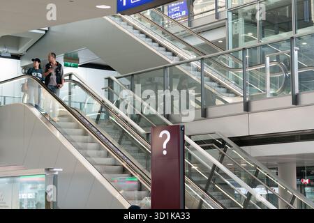 Hong Kong, Cina - 20 settembre 2025: Persone che scendono su una scala mobile all'aeroporto internazionale di Hong Kong. Foto Stock