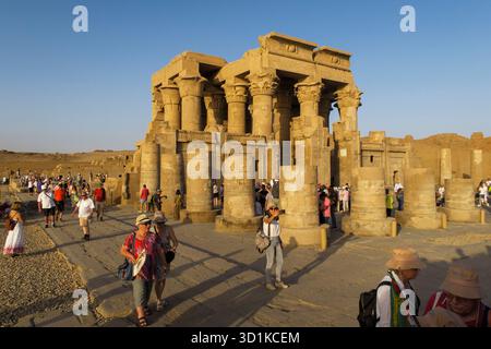 I turisti esplorano l'antico tempio di Kom Ombo con enormi colonne di pietra sotto un cielo azzurro e limpido in Egitto Foto Stock