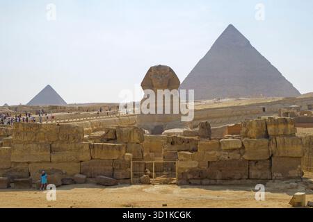 Turisti che esplorano la grande Sfinge e le Piramidi di Giza sotto un cielo limpido in un sito archeologico storico in Egitto Foto Stock