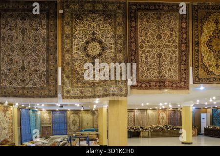 Interno di un negozio di tappeti con una mostra di tappeti tradizionali fatti a mano appesi alle pareti e disposti sul pavimento in Egitto Foto Stock