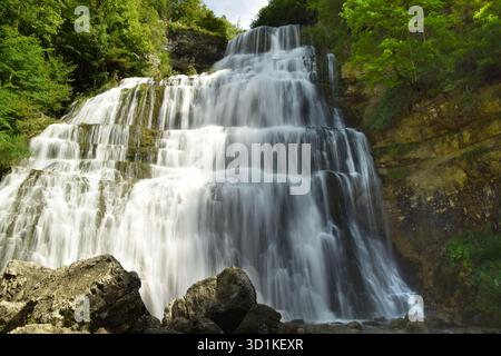 L'acqua si tuffa tra le rocce alla luce del sole alle cascate di Herisson nel villaggio francese di Doucier nella zona del Giura. Foto Stock