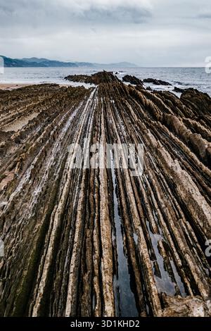 Famosa formazione geologica Flysch nella regione basca di Zumaia in Spagna; strati drammatici che conducono al mare Foto Stock