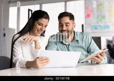 Donna d'affari gioiosa che lavora con un compagno di squadra maschile nell'ufficio Agile Foto Stock