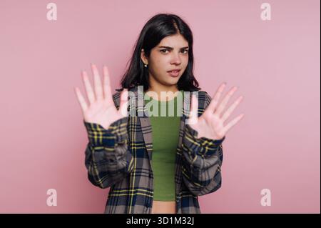 Giovane donna con un'espressione scettica che tiene le mani in alto nel rifiuto. Foto Stock